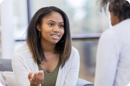 Young female learner sat on a sofa talking to an assessor