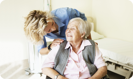 Young female nurse in blue, NHS scrubs with elderly patient in wheelchair