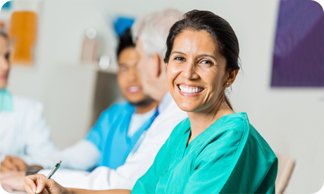 Middle aged, female nurse in green, NHS scrubs smiling