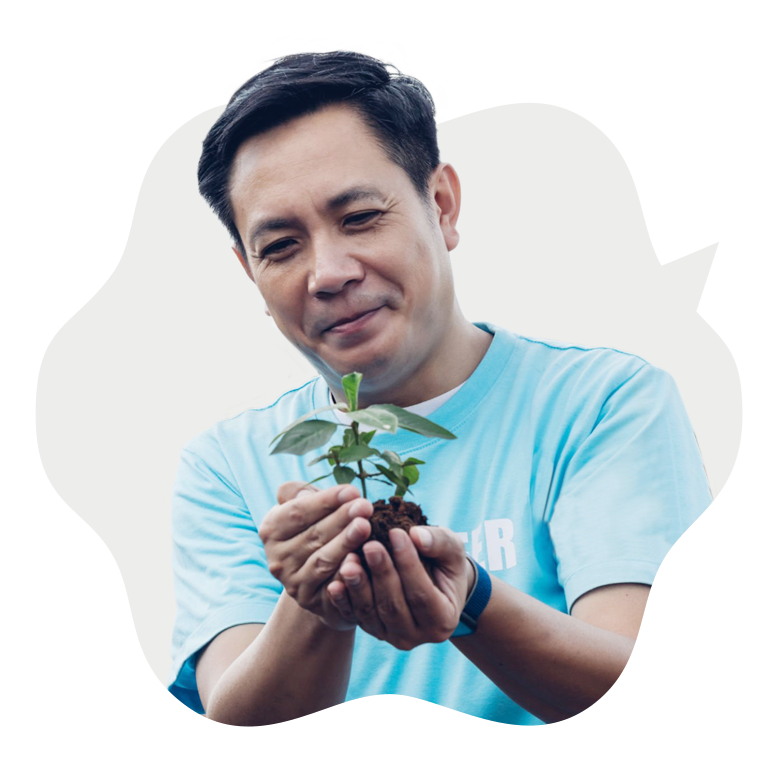 Man looking at a young, green sapling in his hand